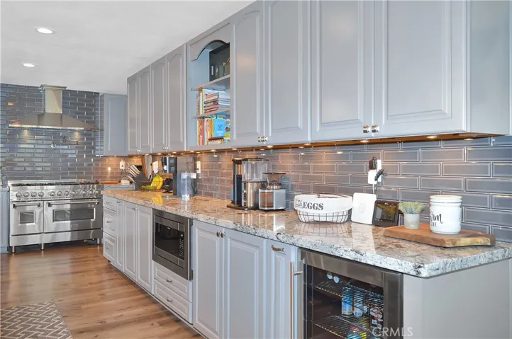 Wow! This fantastic kitchen remodel boasts seating for eight at the "chef's table" style bar, stainless steel appliances (with TWO dishwashers, a professional quality range with pot filler, refrigerator, microwave, and beverage fridge), gorgeous granite countertops, full tile backsplash, two-tone cabinetry (yes, there are cabinets on BOTH sides of the bar), fabulous lighting, pop-up outlets with phone chargers, and a walk-in pantry!