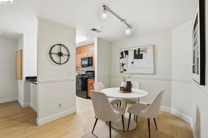 Open dining area featuring wood-finish flooring, track lighting, and wainscoting