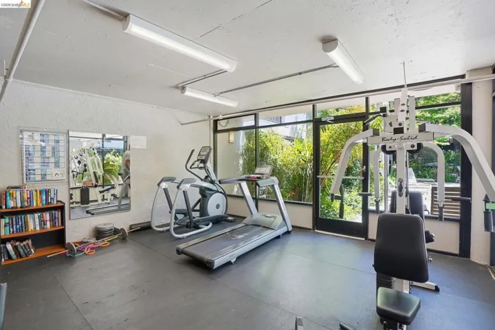 Dedicated fitness area featuring rubberized flooring, abundant natural light from large windows, and direct outdoor access