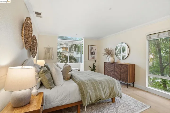 Bright bedroom featuring light wood-finish flooring and crown molding