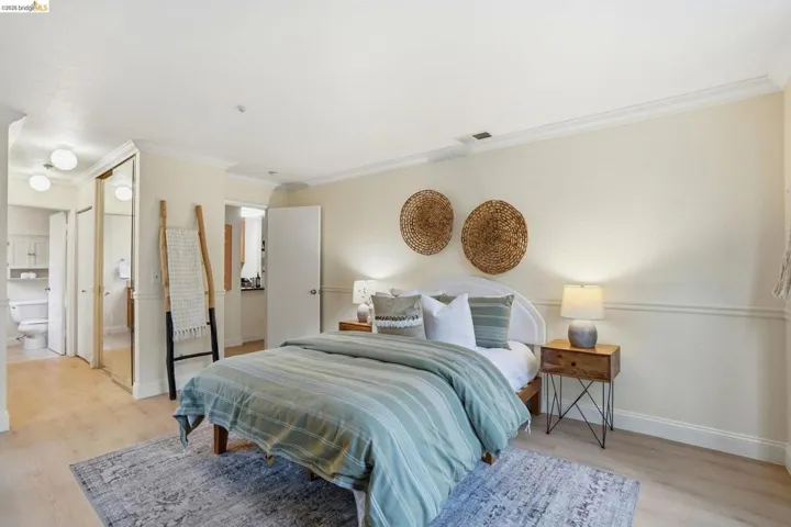 Bedroom featuring light-tone wood-finish flooring, white crown molding, and a neutral wall color