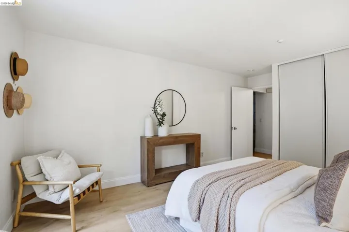 Spacious sleeping area featuring light wood-finish flooring, white walls, and a built-in closet with sliding doors