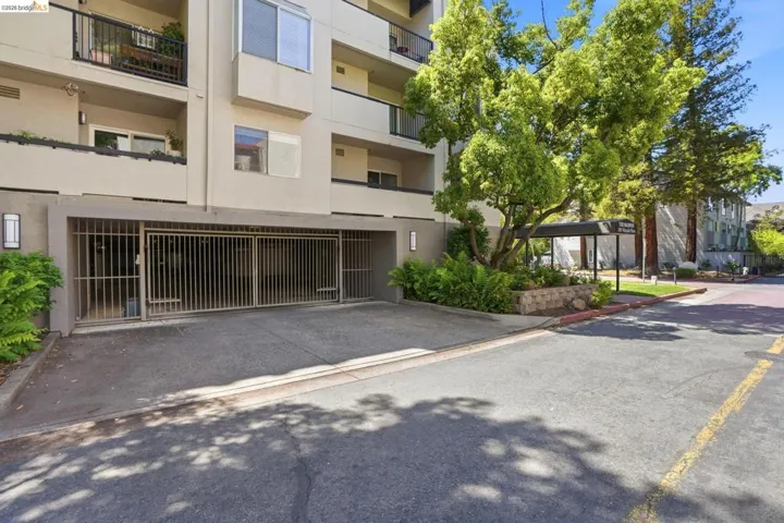 Multi-story building exterior featuring a secure gated parking entrance
