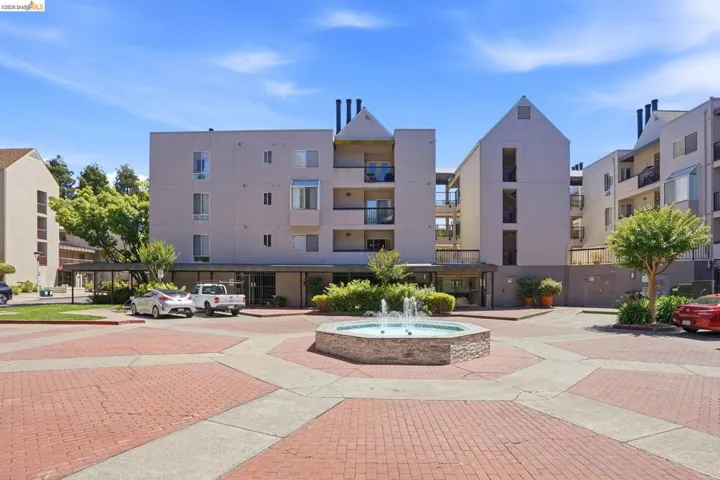 Central courtyard featuring a fountain with stone surround, brick-patterned hardscaping, and mature landscaping