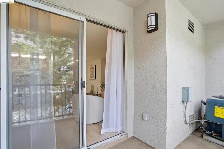 Private patio space with stucco walls and an outdoor wall light fixture
