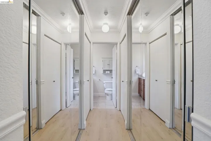 Hallway featuring mirrored sliding closet doors and light wood-finish flooring