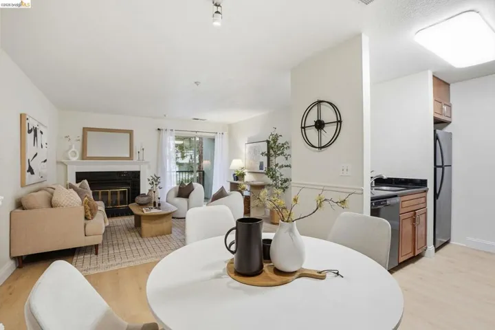 Open-concept living space with light-tone wood-finish flooring, a white mantel fireplace, and a sliding glass door