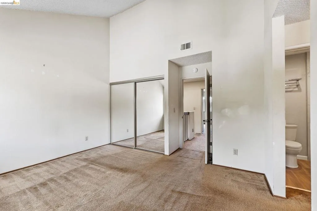 Unfurnished bedroom featuring light carpet, a closet, and a high textured ceiling