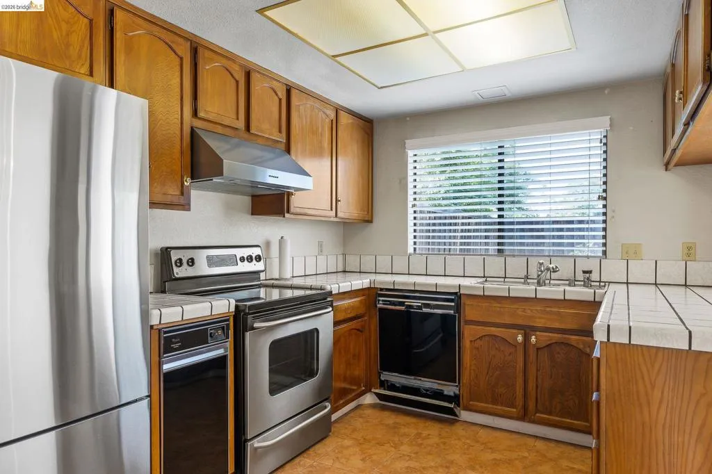 Kitchen with tile countertops, stainless steel appliances, and wood finish cabinets
