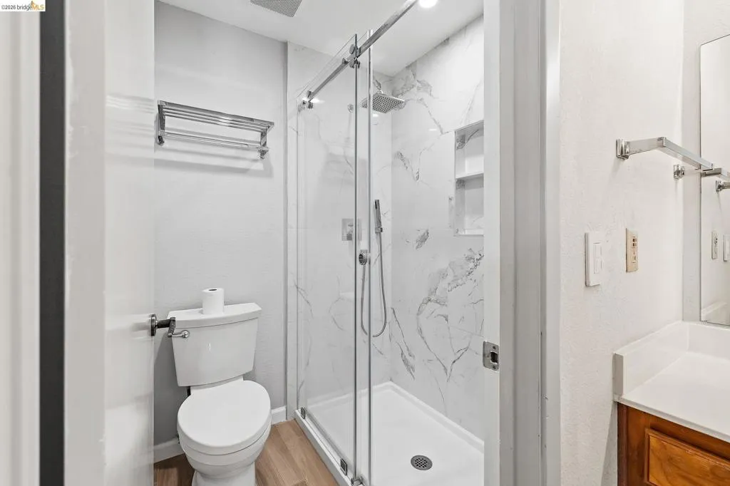 Full bath with vanity, a marble finish shower, and light wood-type flooring