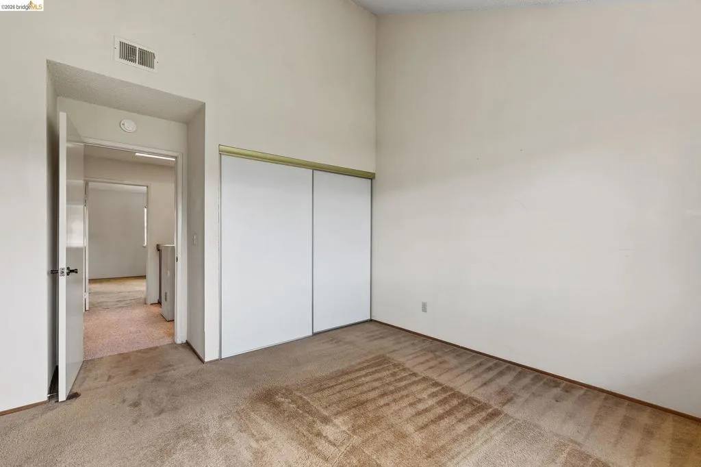 Unfurnished bedroom with light colored carpet, a closet, and a high ceiling