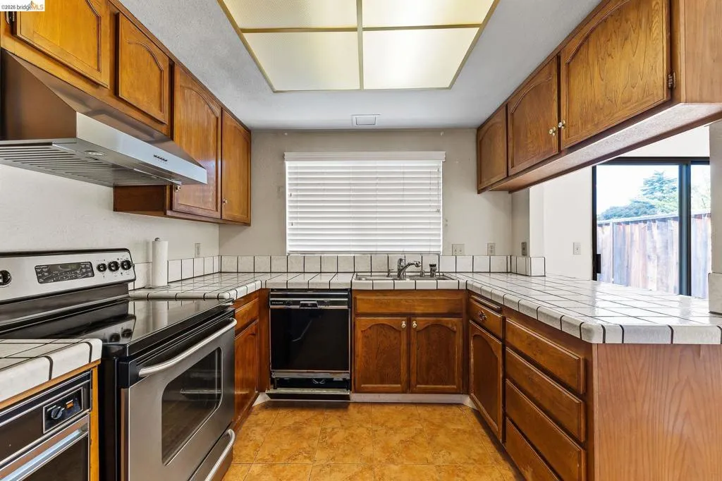 Kitchen featuring tile counters, stainless steel electric range, a peninsula, and dishwasher