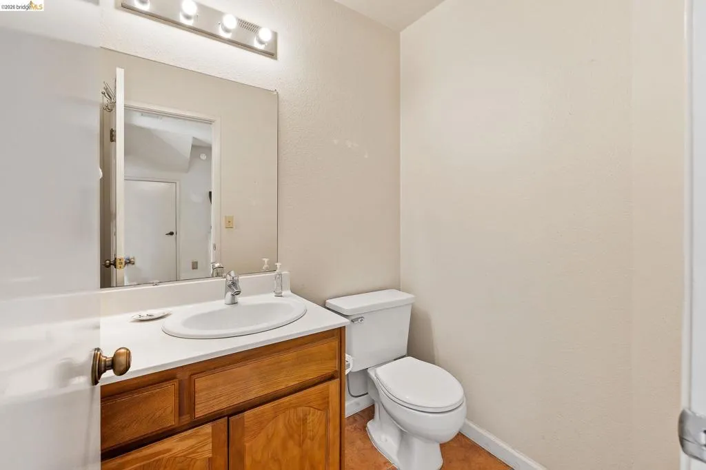 Half bathroom featuring vanity and a textured wall