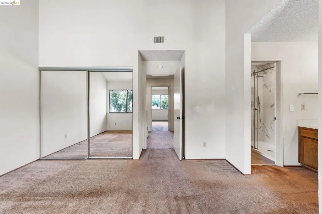 Unfurnished bedroom with light colored carpet, a closet, and ensuite bath