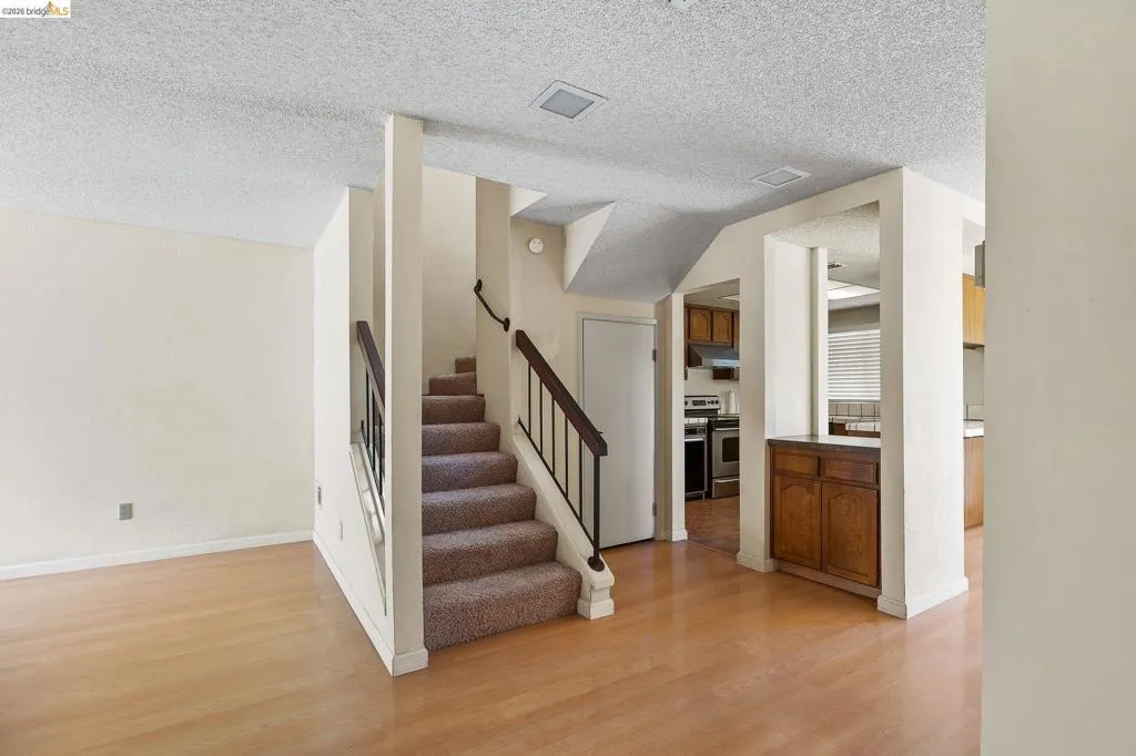 Stairs with a textured ceiling and wood finished floors