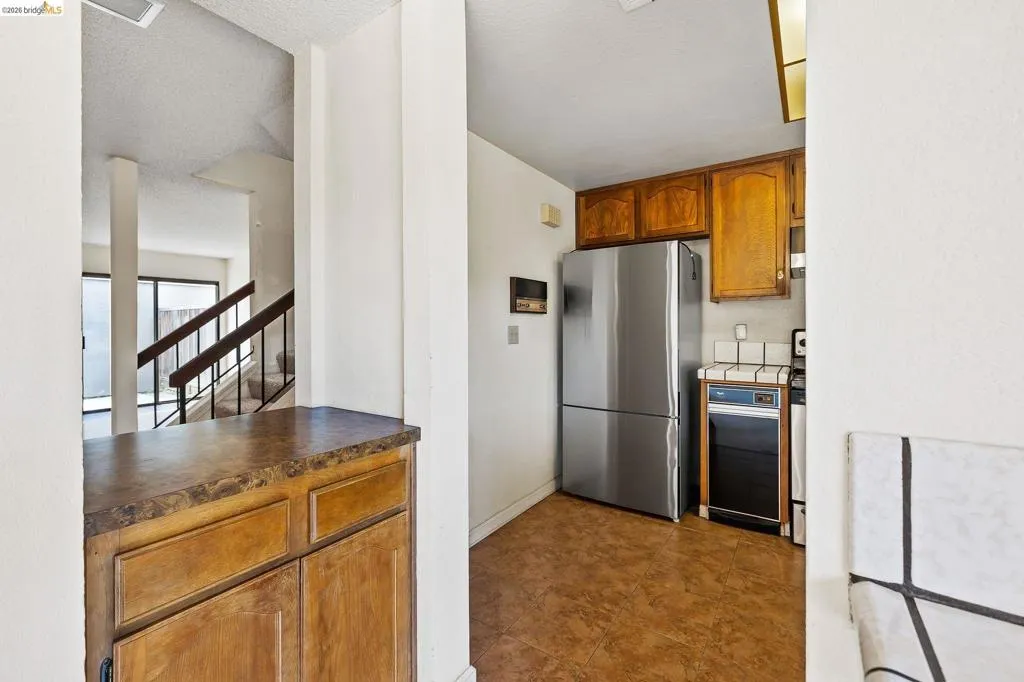 Kitchen with wood finish cabinets, freestanding refrigerator, dark countertops, and a textured ceiling