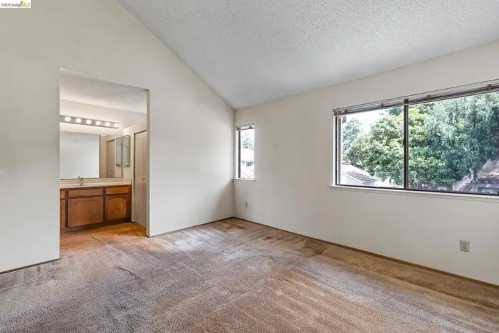 Unfurnished bedroom with light colored carpet and ensuite bath