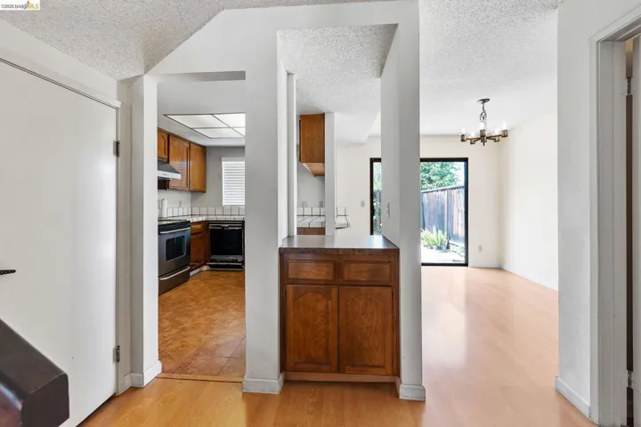 Kitchen with suspended lighting, wood finish cabinets, dishwasher, dark countertops, and light wood finished floors