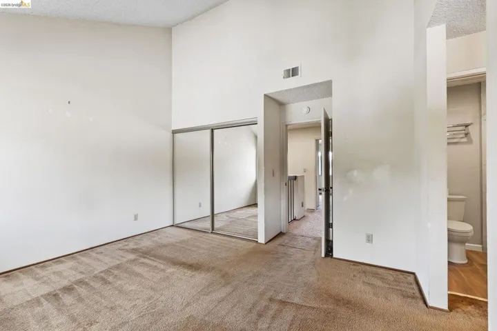 Unfurnished bedroom featuring light carpet, a closet, and a high textured ceiling