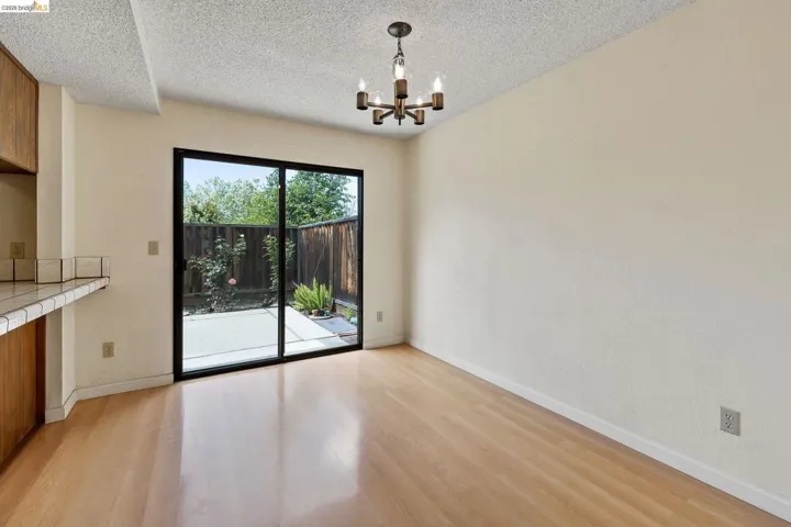 Unfurnished dining area featuring hanging lights, light wood-type flooring, and a textured ceiling