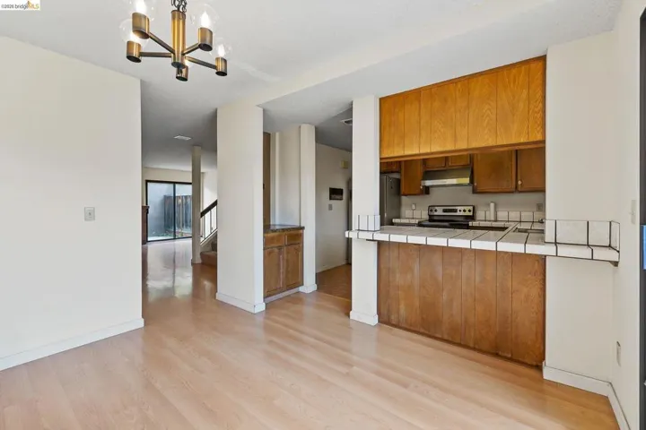 Kitchen featuring tile countertops, wood finish cabinets, light wood-type flooring, a peninsula, and stainless steel appliances