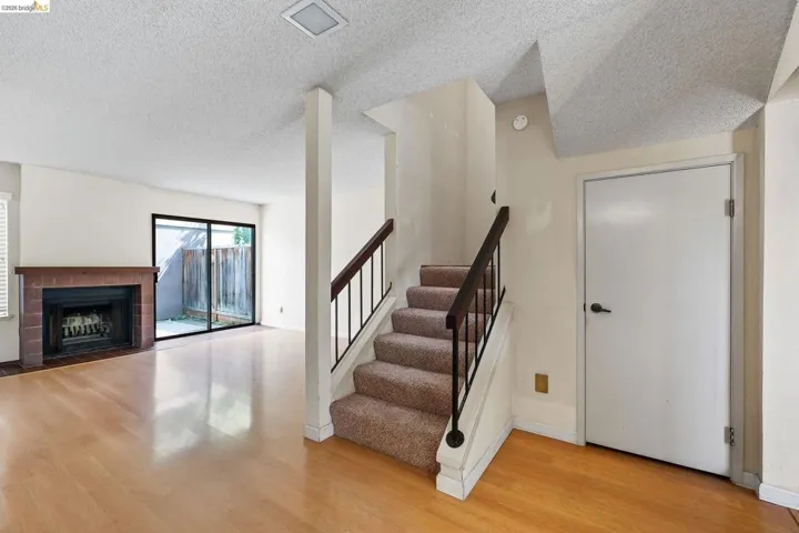 Staircase with a tiled fireplace, wood finished floors, and a textured ceiling