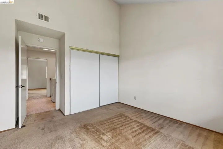 Unfurnished bedroom with light colored carpet, a closet, and a high ceiling