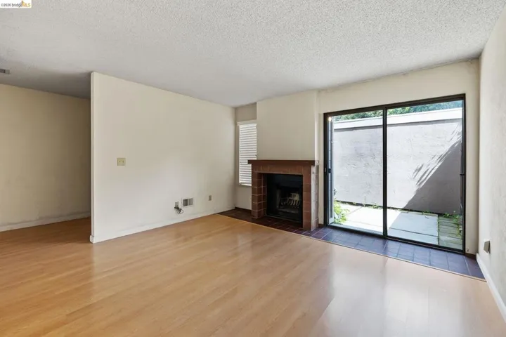 Unfurnished living room featuring a tile fireplace, light wood-type flooring, and a textured ceiling