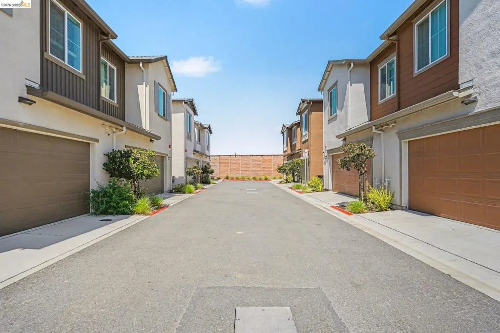 Contemporary townhome architecture featuring stucco and horizontal siding accents, individual two-car garages with panel doors, and clear windows