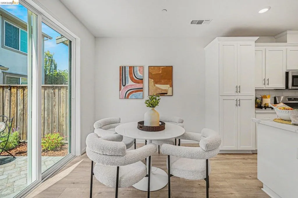 Bright dining area with wood-finish flooring and a sliding glass door leading to a private outdoor space