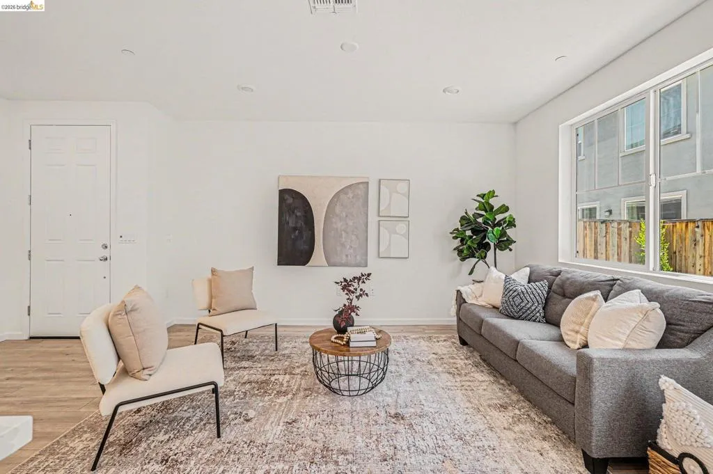 Open-concept living area featuring light wood-finish flooring, recessed lighting, and a large window