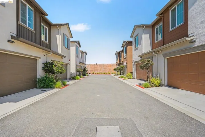 Contemporary townhome architecture featuring stucco and horizontal siding accents, individual two-car garages with panel doors, and clear windows