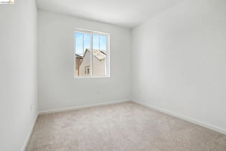 Room featuring light neutral-toned walls, a white-framed window, and neutral-toned carpet flooring