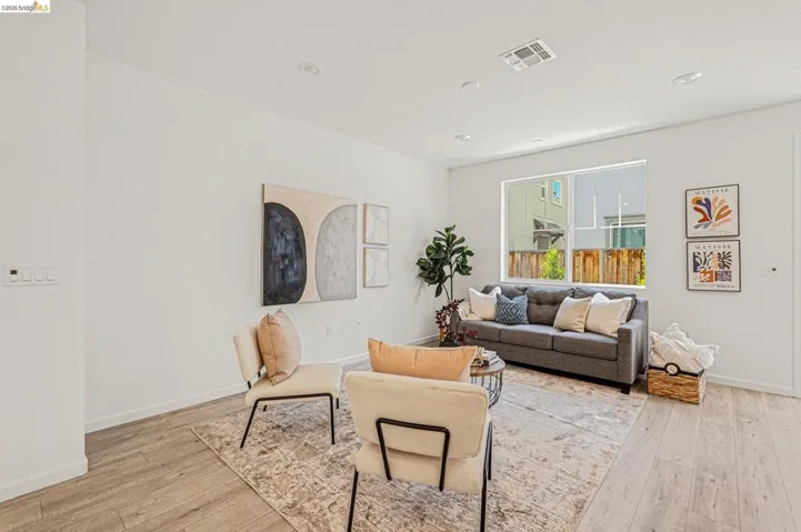 Living area featuring light wood-finish flooring, recessed ceiling lights, and a large window