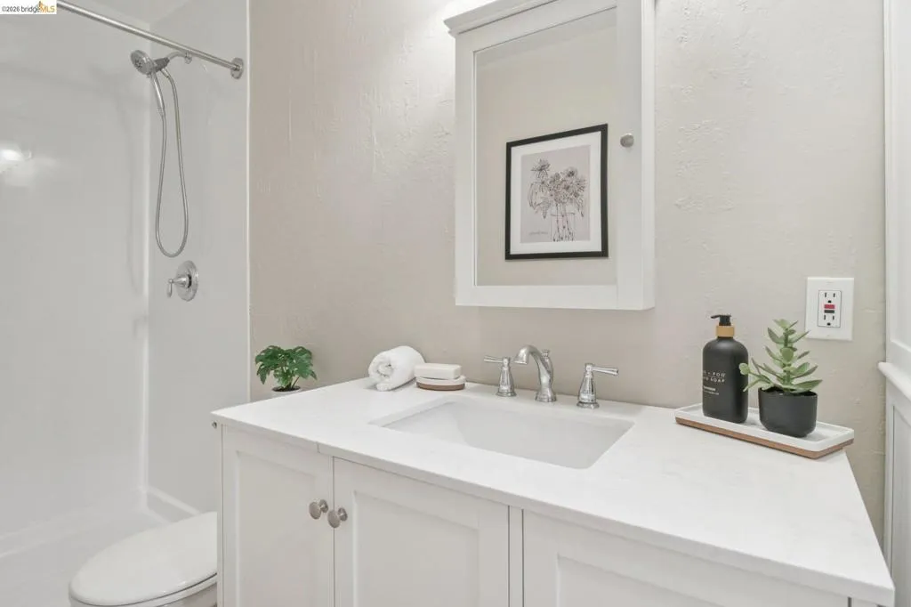 Bathroom featuring vanity, a textured wall, and a shower stall