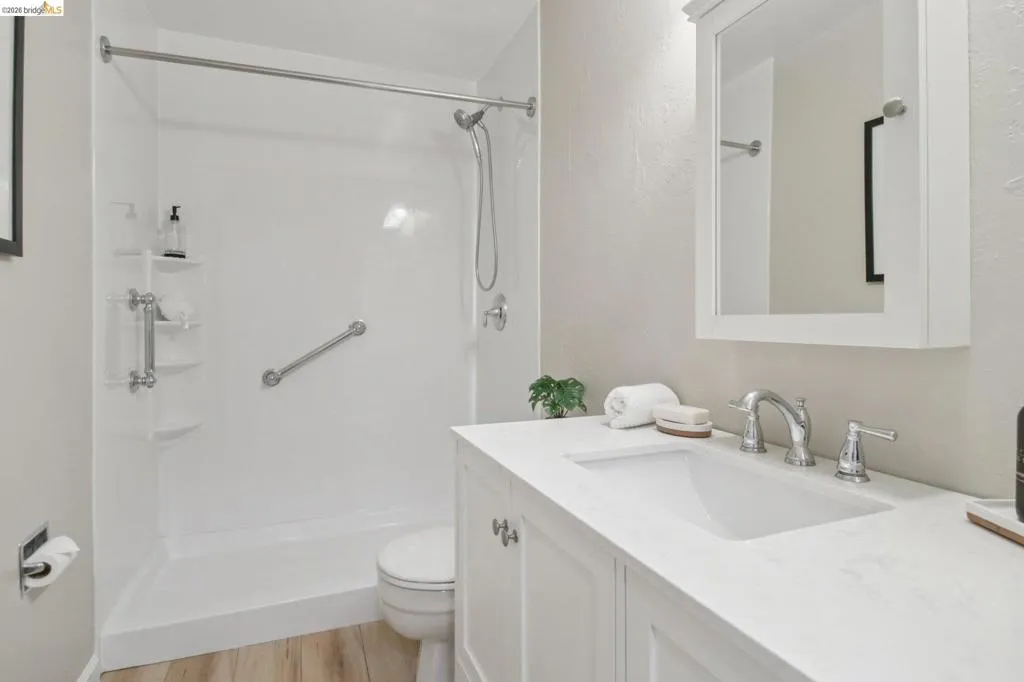 Bathroom featuring vanity, a stall shower, and light wood-style floors