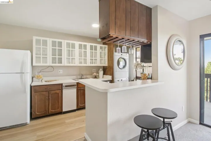Kitchen with light countertops, freestanding refrigerator, glass insert cabinets, a breakfast bar, and recessed lighting