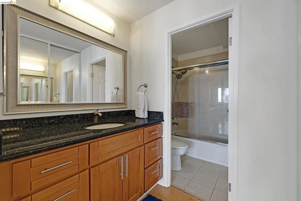 Bathroom featuring vanity, shower / bath combination with glass door, and light tile patterned floors