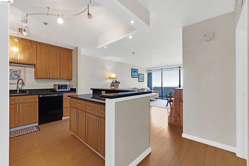 Kitchen featuring light wood-style floors, wood finish cabinets, dishwasher, a kitchen island, and expansive windows