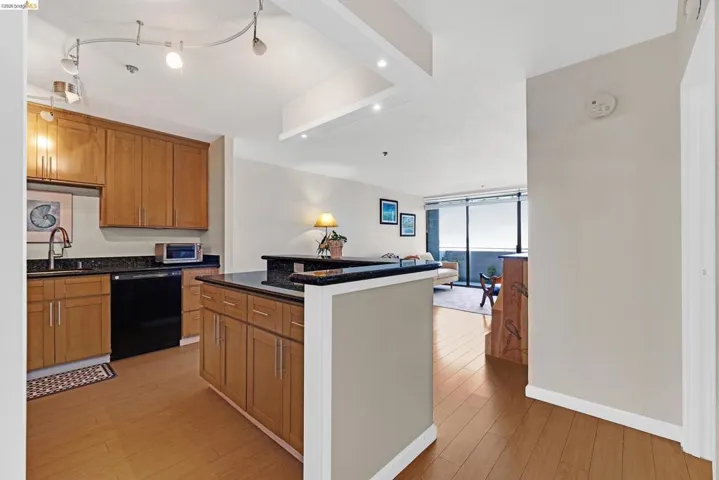 Kitchen featuring light wood-style floors, wood finish cabinets, dishwasher, a kitchen island, and expansive windows