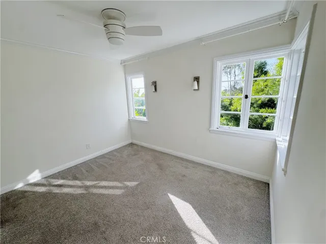 Bright primary bedroom with a comfortable king-size bed, large windows offering ample natural light and stylish, relaxing ambiance.