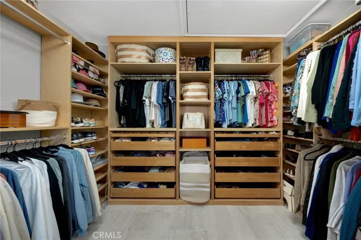 Beautifully designed primary walk-in closet featuring custom built-in organizers and abundant storage