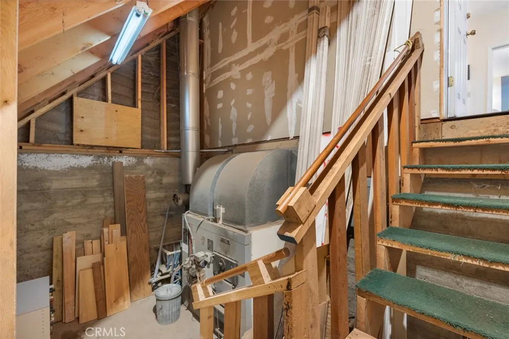 Stairs to basement area with wood burning furnace.