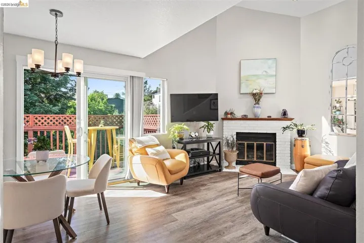 living area with wood finished floors, a fireplace, vaulted ceiling, and suspended lighting