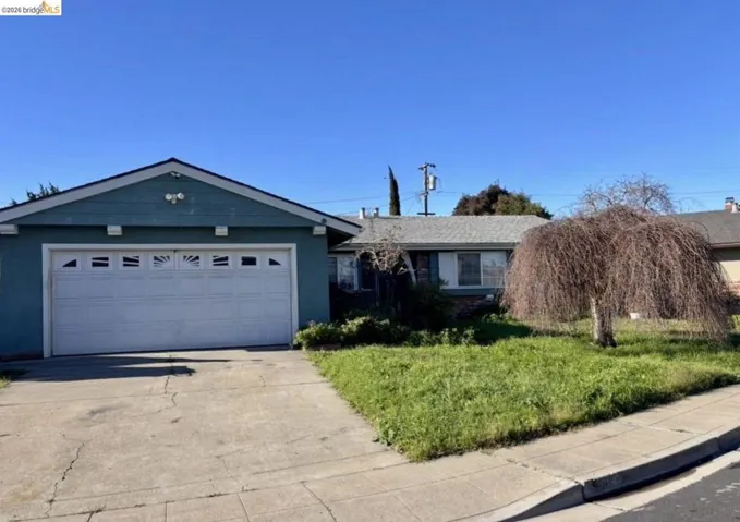 Ranch-style house featuring driveway, a garage, stucco siding, and a front lawn