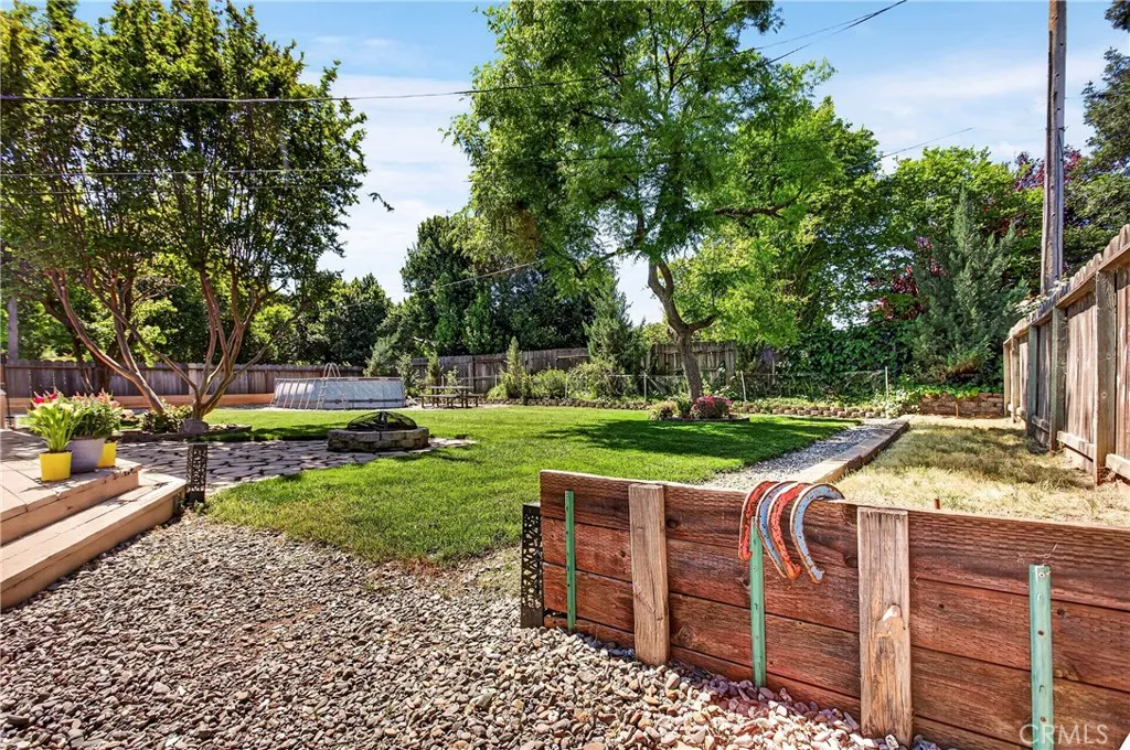 angled shot of the backyard, there are fruit trees and to the right there is a horse pitts