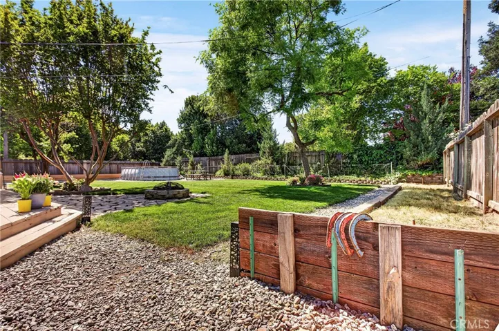 angled shot of the backyard, there are fruit trees and to the right there is a horse pitts