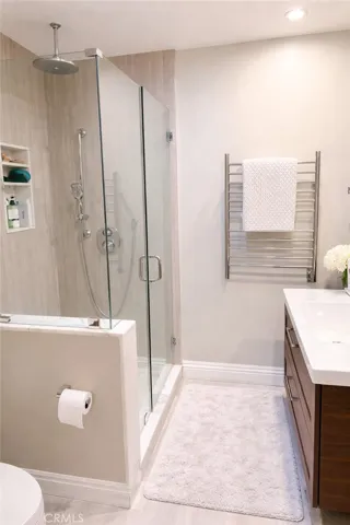 Bathroom with marble shower, heated towel warmer and plenty of storage. Skylight