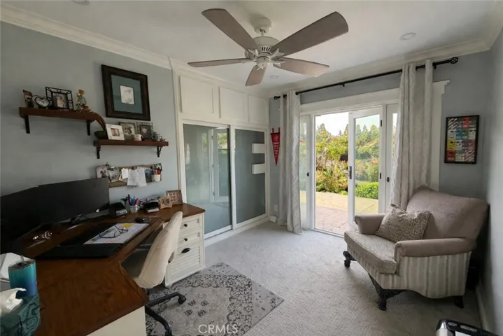 Bedroom used as an office with built-in closet organizer, storage, and door out to courtyard