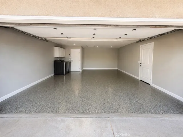 3 car garage with epoxy floor and rollup door, two attic storage areas, washer & dryer with cabinets, door with separate entrance to side area.